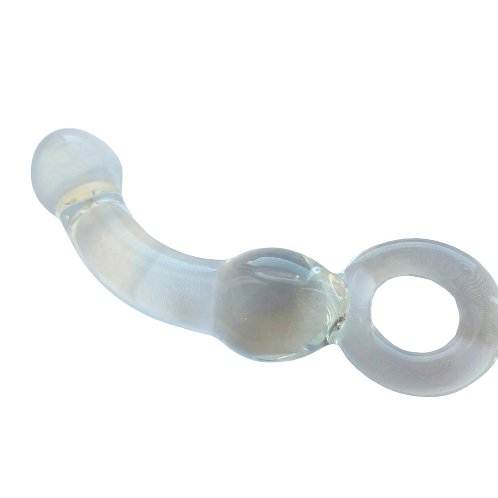 A clear glass curved wand with a ring handle, resting on a white fabric surface.