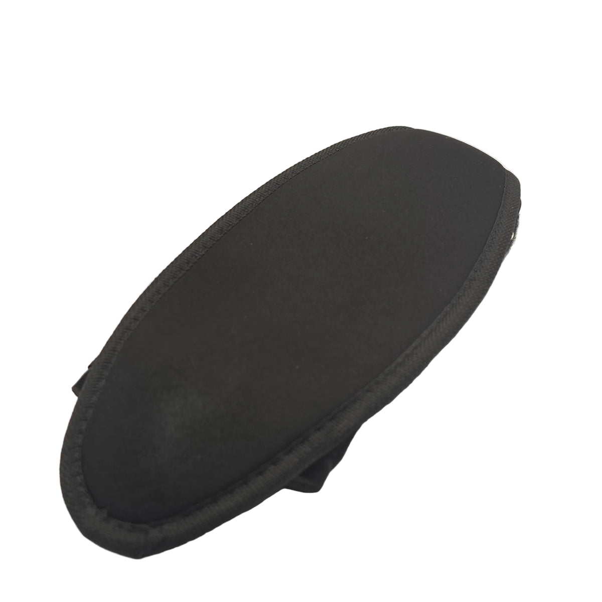 A black neoprene or fabric-covered hard case with a rounded rectangular shape and stitched edges, shown on a white fabric surface next to a black plastic bag.
