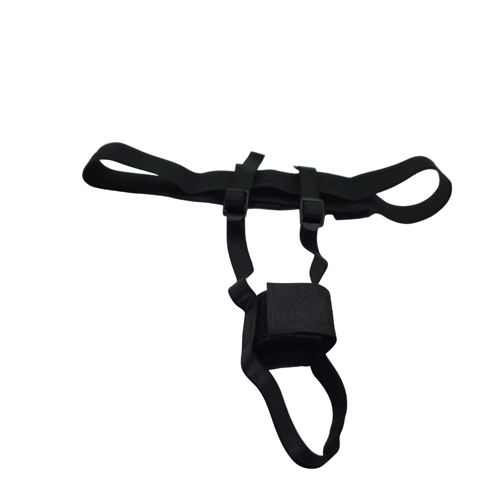 A black adjustable harness-style strap accessory with plastic buckles and a central loop, laid on a white satin-like fabric surface.