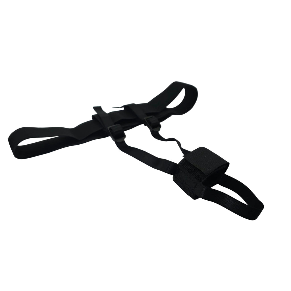 A black adjustable strap harness with a plastic buckle, laid out on a white satin fabric inside a white box.