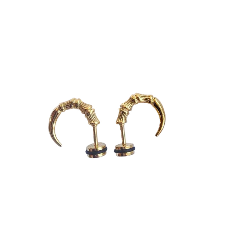 A pair of gold-toned claw-shaped earrings with black circular accents at the posts, displayed on a light blue fabric background.