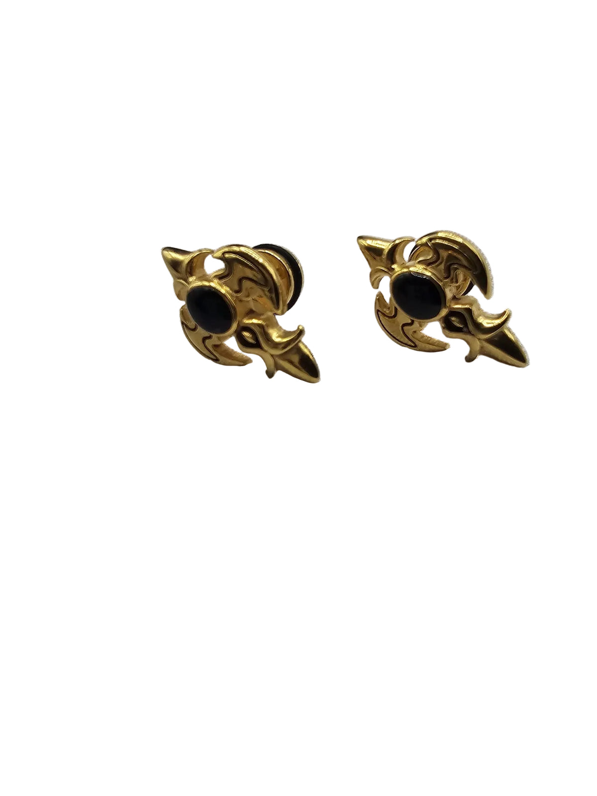 A pair of gold-toned gothic-style stud earrings with black circular centers, displayed on a textured light gray fabric surface.