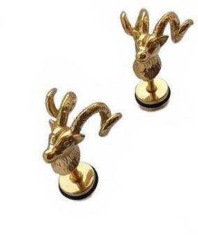 A pair of gold-toned stud earrings shaped like ram or goat heads with curved horns, mounted on round black backing discs, shown on a plain white background.